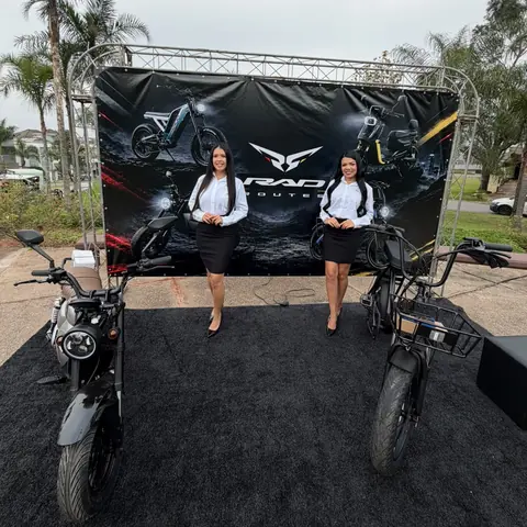 Duas promotoras em frente ao painel da Rad Routes com motos elétricas expostas